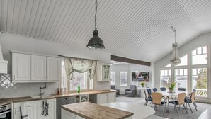 Una cocina amplia con armarios blancos, una isla de madera y un comedor grande con vistas al exterior.