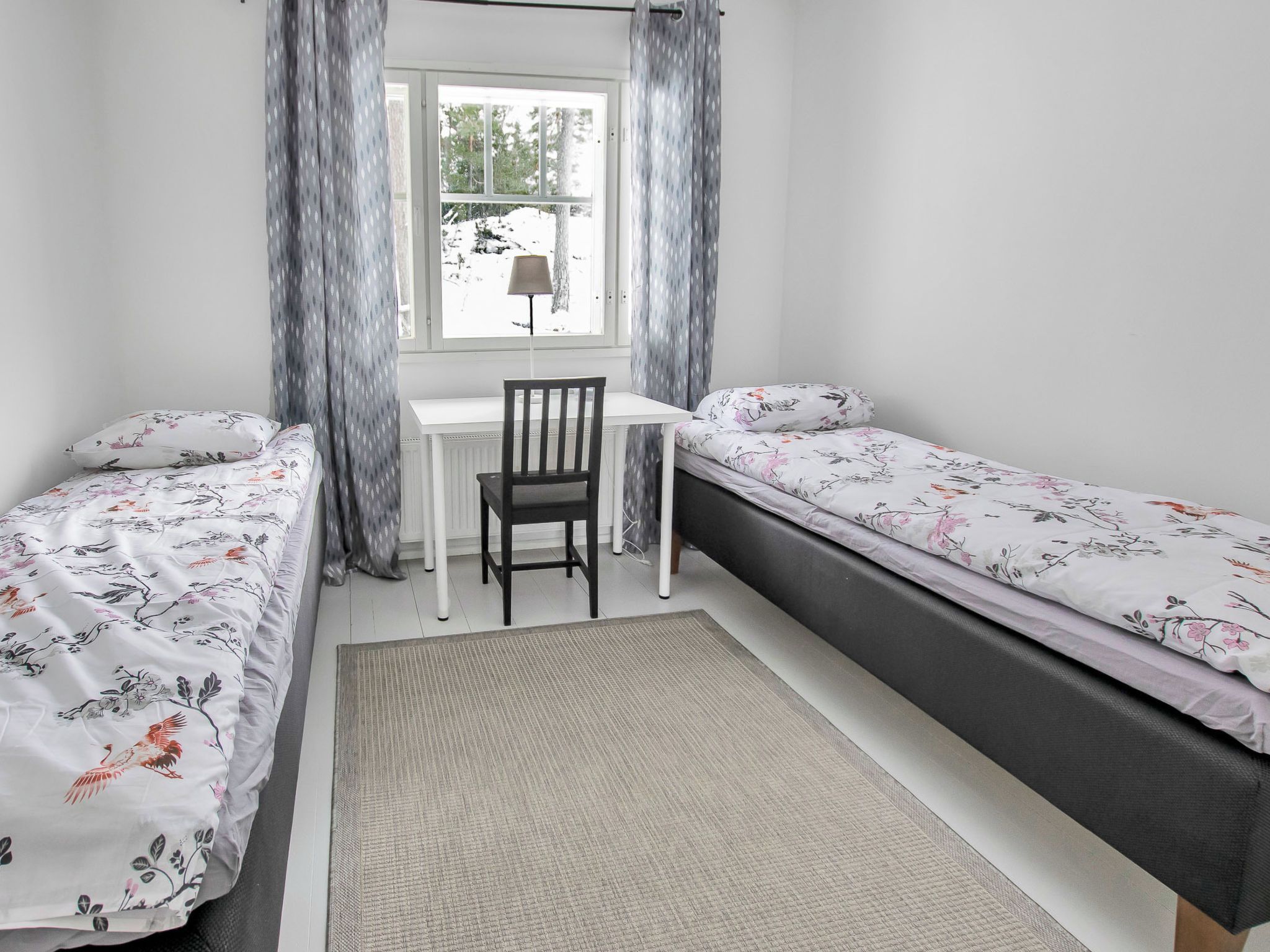A bedroom with two single beds, a desk, and a chair.