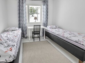 A bedroom with two single beds, a desk, and a chair.
