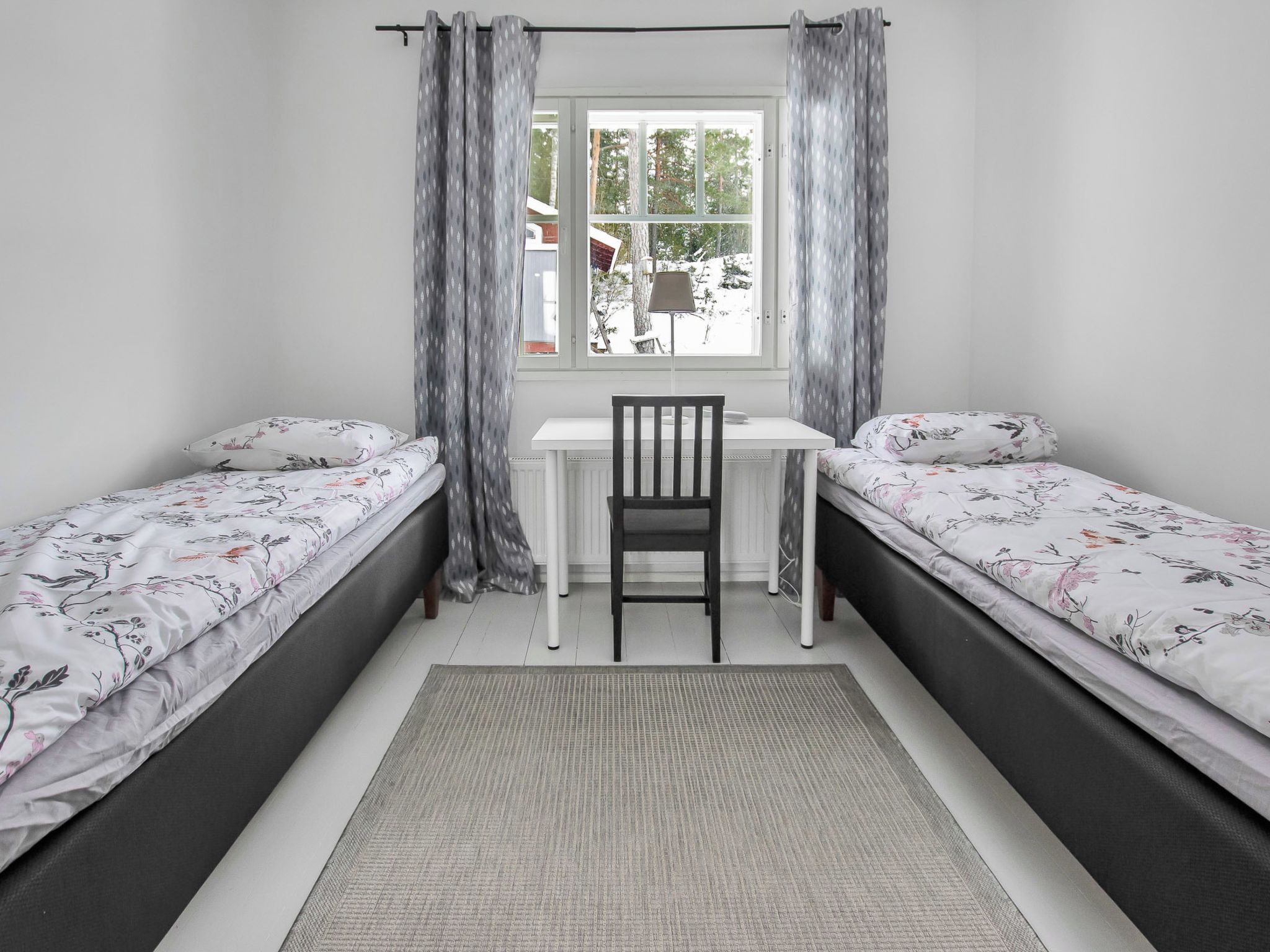 A bedroom with two single beds, a desk, and a chair.