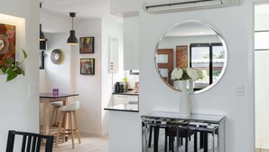 Une cuisine moderne avec un miroir rond, un coin repas avec une table et des chaises blanches, et des œuvres d’art accrochées aux murs.