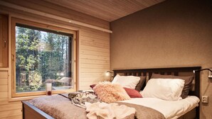 Un dormitorio con una cama de madera, un ventanal y vistas a árboles.