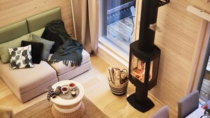 Una sala de estar acogedora con un sofá, una mesita con bebidas, una chimenea y vistas al exterior.