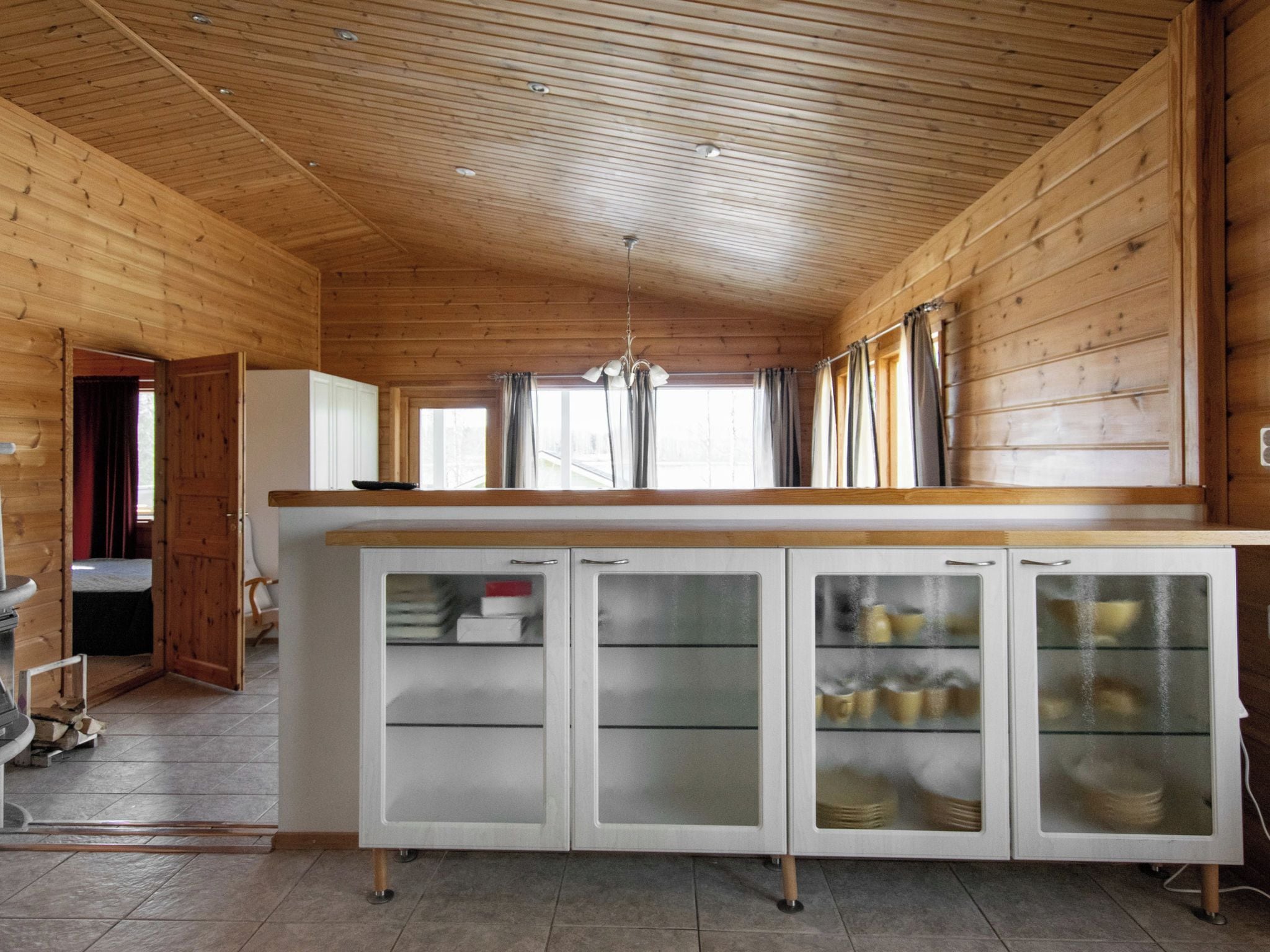 Un intérieur en bois avec un espace cuisine comprenant un îlot central doté de placards et d’un réfrigérateur.