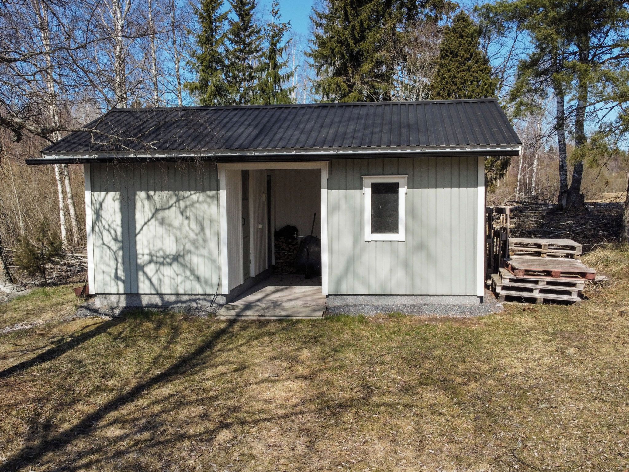 En liten, envåningsbyggnad med ett tak av metall och en dörr som leder in till ett inre utrymme.