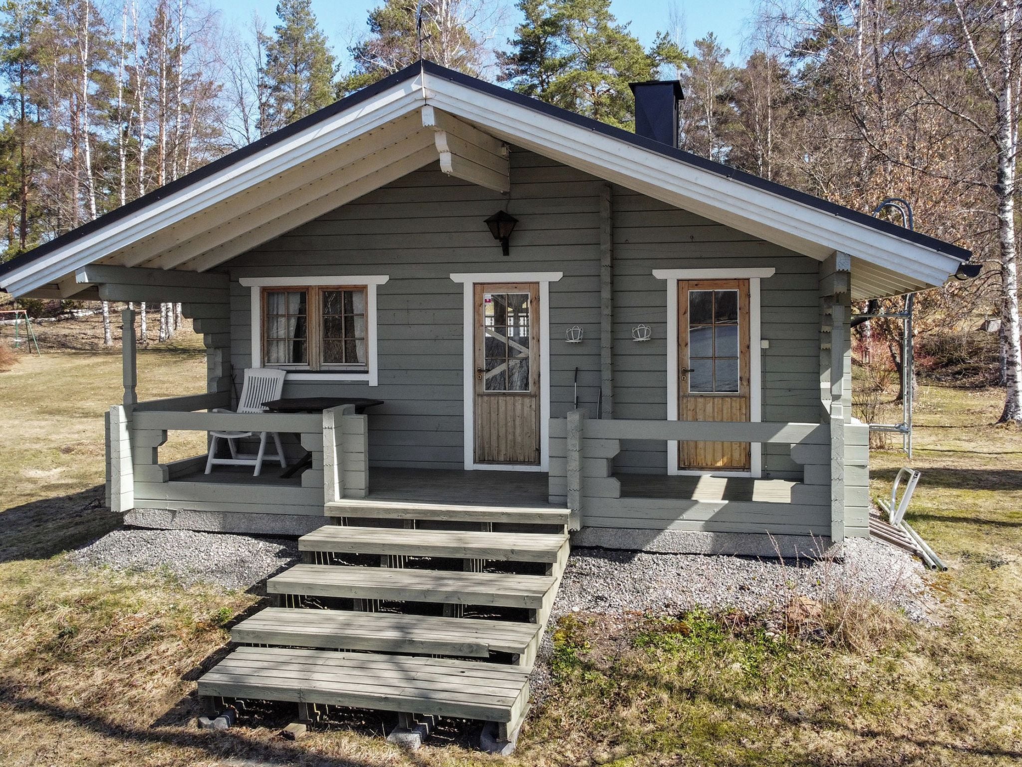 Une cabane avec une véranda, deux portes et une cheminée.