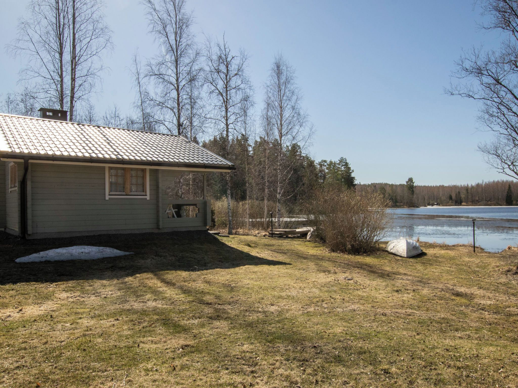 A single-story house with a tiled roof, a small porch, and a yard with a pond.