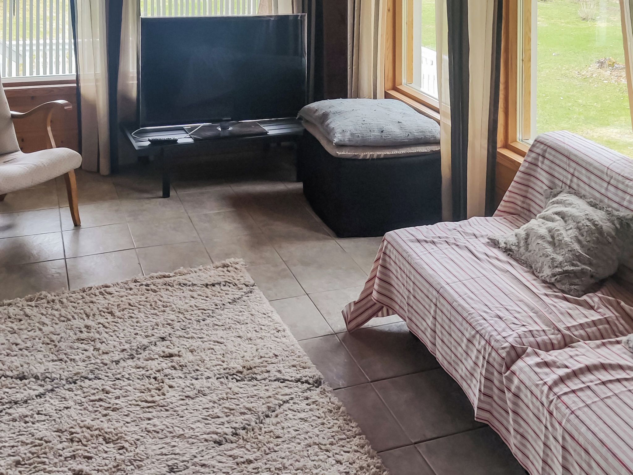 Un salon avec un canapé, un téléviseur, un piano et un tapis.