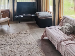 A living room with a sofa, a television, a piano, and a rug. - Ketunkolo by Interhome (Tampere)