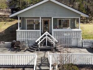 A two-story cabin with a porch, a staircase, and outdoor seating.