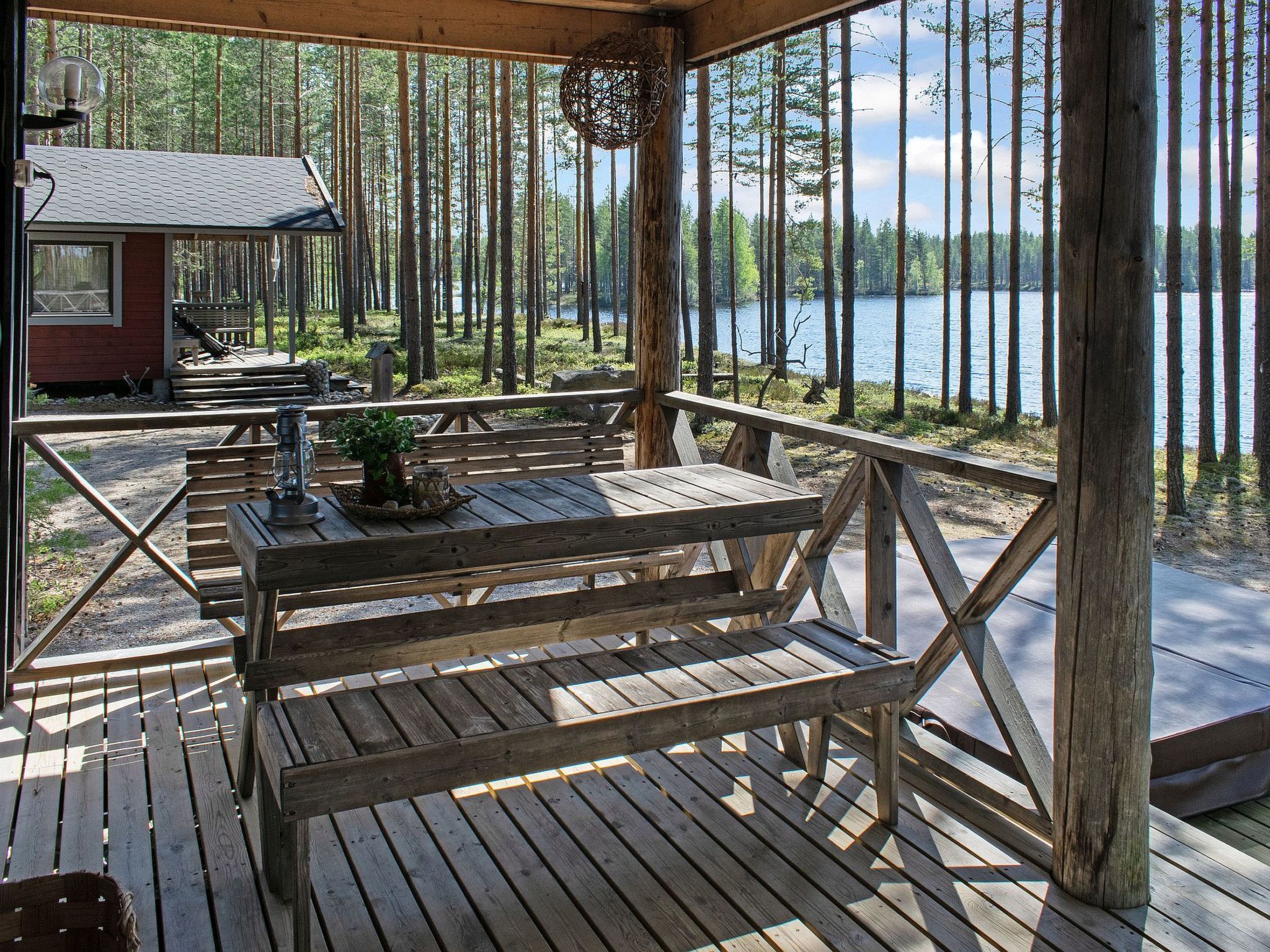 Eine Holzterrasse mit Picknicktischen und Bänken mit Blick auf einen See.