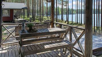Eine Holzterrasse mit Picknicktischen und Bänken mit Blick auf einen See.
