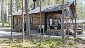 Un chalet rustique doté d’une véranda, entouré de grands arbres.