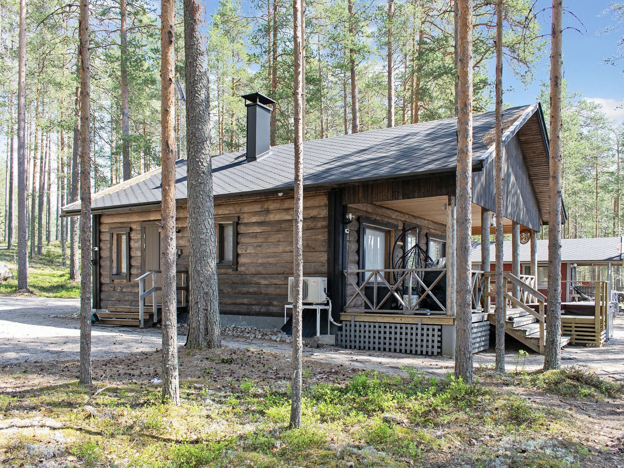 A log cabin with a porch, a chimney, and a deck.