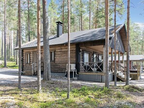 Une cabane en rondins avec une véranda, une cheminée et une terrasse.