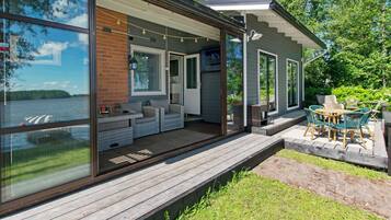 Una casa moderna con un'ampia vetrata, un terrazzo in legno e mobili da esterno.