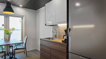 Una cucina moderna con frigorifero in acciaio inox, pensili in legno, un lavello e un'area pranzo con tavolo e sedie.