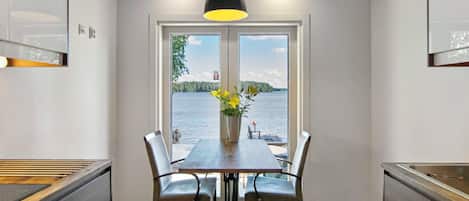Un espace repas comprenant une table, des chaises et donnant sur un lac.