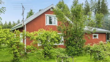 A red wooden house with a white window and a small porch.