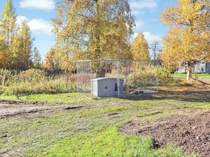 A fenced outdoor area with a utility shed, grass, and trees with autumn leaves. - Laattajan hirsipirtti by Interhome (Ukkohalla)