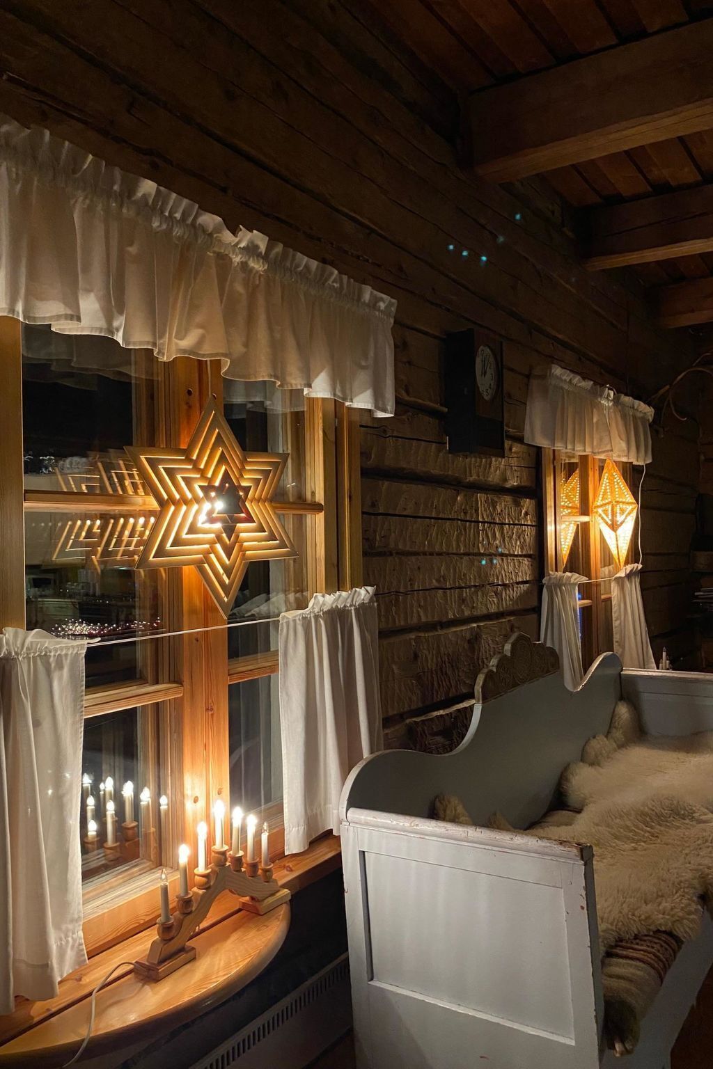 Interior acogedor de una cabaña con techo de madera, pared de ladrillo rústica y una cama con cubierta blanca y esponjosa.