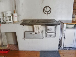 Une cuisine équipée d’une cuisinière, d’une machine à café et d’un balai.