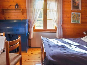 A room with a bed, a desk, a chair, a window with curtains, and a painting on the wall.