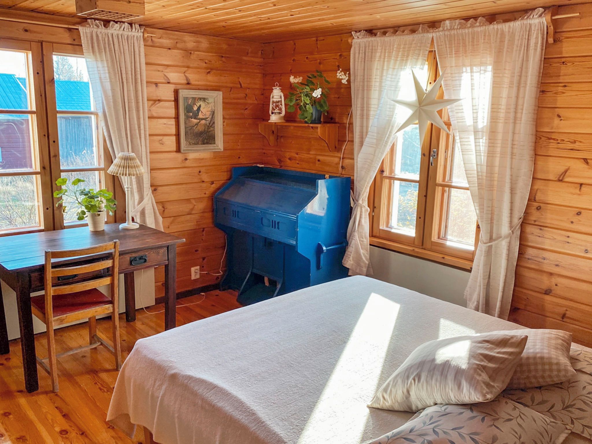 Una habitación de cabaña de madera con una cama, un escritorio y un mueble de almacenamiento azul.