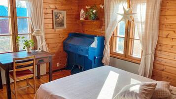 Una habitación de cabaña de madera con una cama, un escritorio y un mueble de almacenamiento azul.