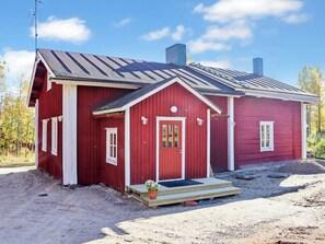 A red wooden house with a sloped roof, a front porch, and a chimney. - Laattajan hirsipirtti by Interhome (Ukkohalla)