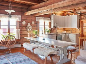 Une cuisine rustique avec des poutres en bois, un grand îlot central et un luminaire suspendu.