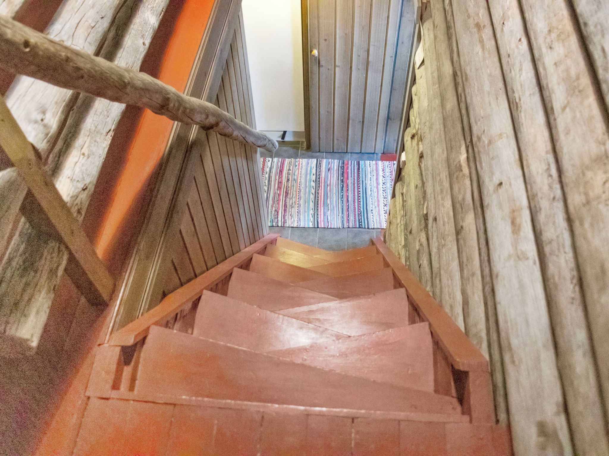 Un escalier en bois, doté d’une rampe, mène à une porte.