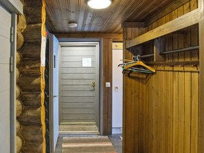 Un pasillo con una puerta de madera, un perchero y un tapete estampado.