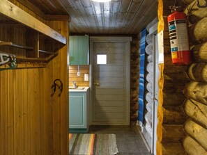 A narrow hallway with a wooden door, a small kitchen area, and a fire extinguisher mounted on the wall.