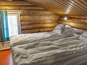 Un dormitorio con techo de madera, cama con ropa de cama blanca y ventana con cortinas.