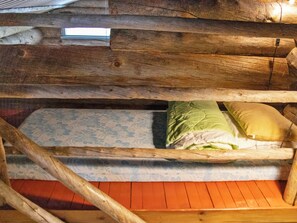 A bunk bed with a mattress and pillows, wooden beams, a window, and a wooden floor. - Kelopirtti by Interhome (Pelkosenniemi)