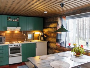 A modern kitchen with green cabinets, a stove, and a coffee maker. - Kelopirtti by Interhome (Pelkosenniemi)