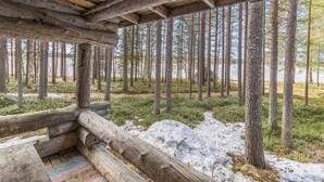 Eine rustikale Holzhütte mit geneigtem Dach, umgeben von dichtem Wald und einem See.