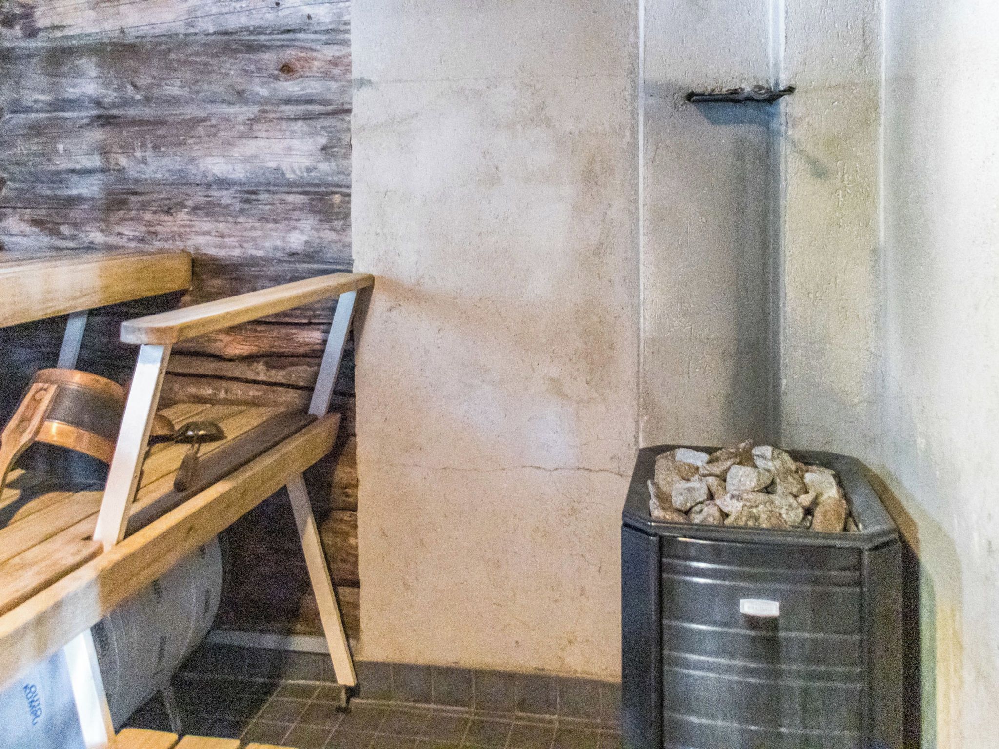 En hörna i ett rum med en träbänk, en papperskorg och en vägg med en tydlig struktur.