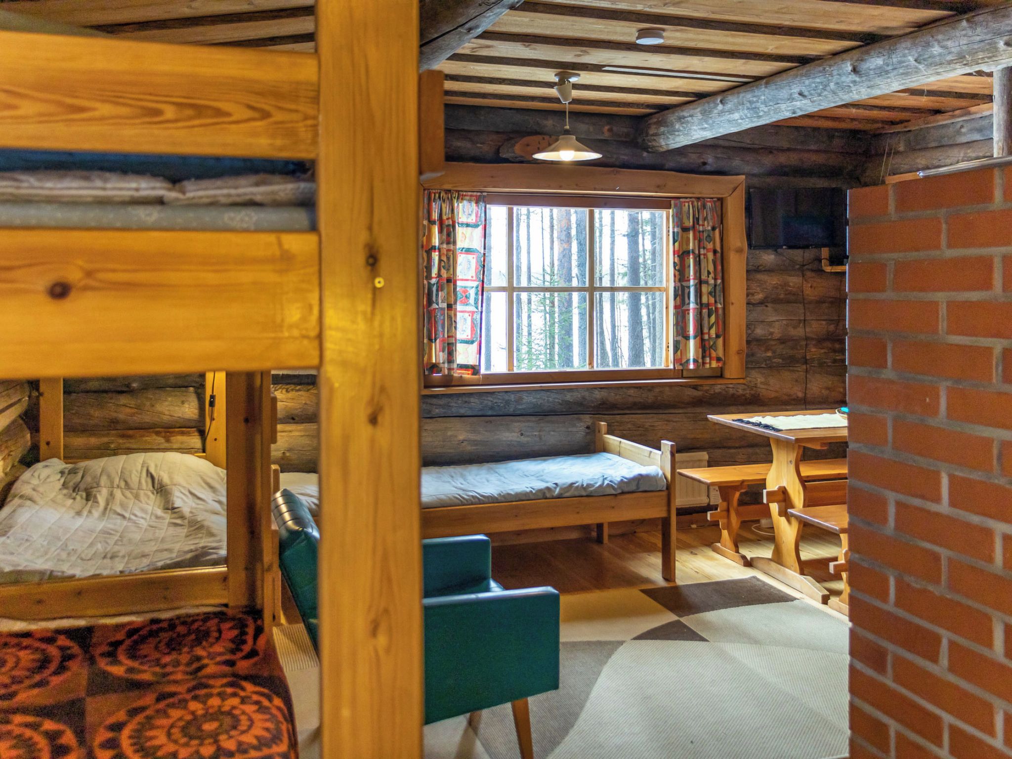 Ein rustikales Blockhaus-Interieur mit einem hölzernen Bett, einer Bank, einem Tisch und einem Fenster mit Vorhängen.