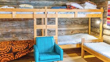 Ein Zimmer mit Etagenbetten, einem blauen Stuhl und Teppichen mit Muster.