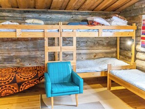 Ein Zimmer mit Etagenbetten, einem blauen Stuhl und Teppichen mit Muster.
