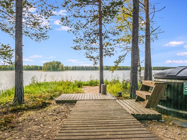 A wooden dock leading to a lake with a covered area and a bench.