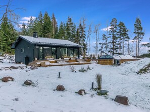A cabin with a large deck and a covered outdoor area, surrounded by snow and trees. - Villa udden by Interhome (Porvoo)