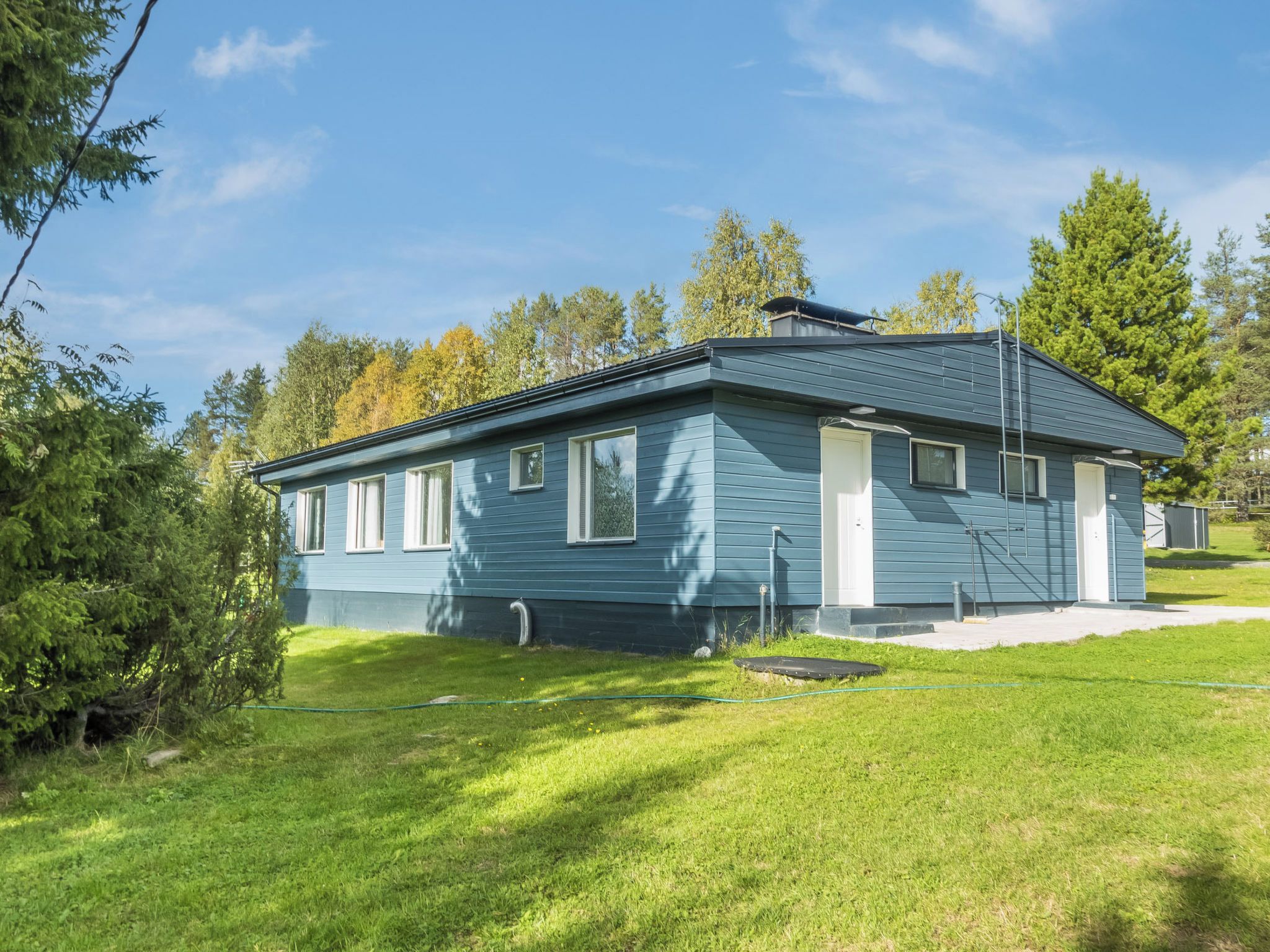 Ein eingeschossiges Haus mit Satteldach, einer Veranda und einem kleinen Vorgarten.