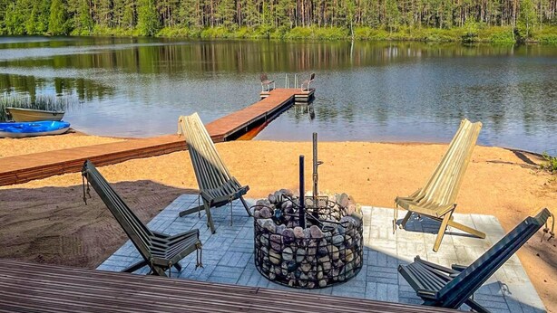 Eine See-Terrasse mit Liegestühlen, einem Feuerkorb und einem Steg, der ins Wasser führt.