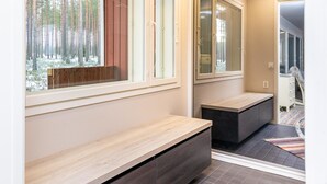 Ein modernes Interieur mit einer Bank, einem Fenster mit Blick auf einen Wald und einem Spiegel, der den Raum widerspiegelt.