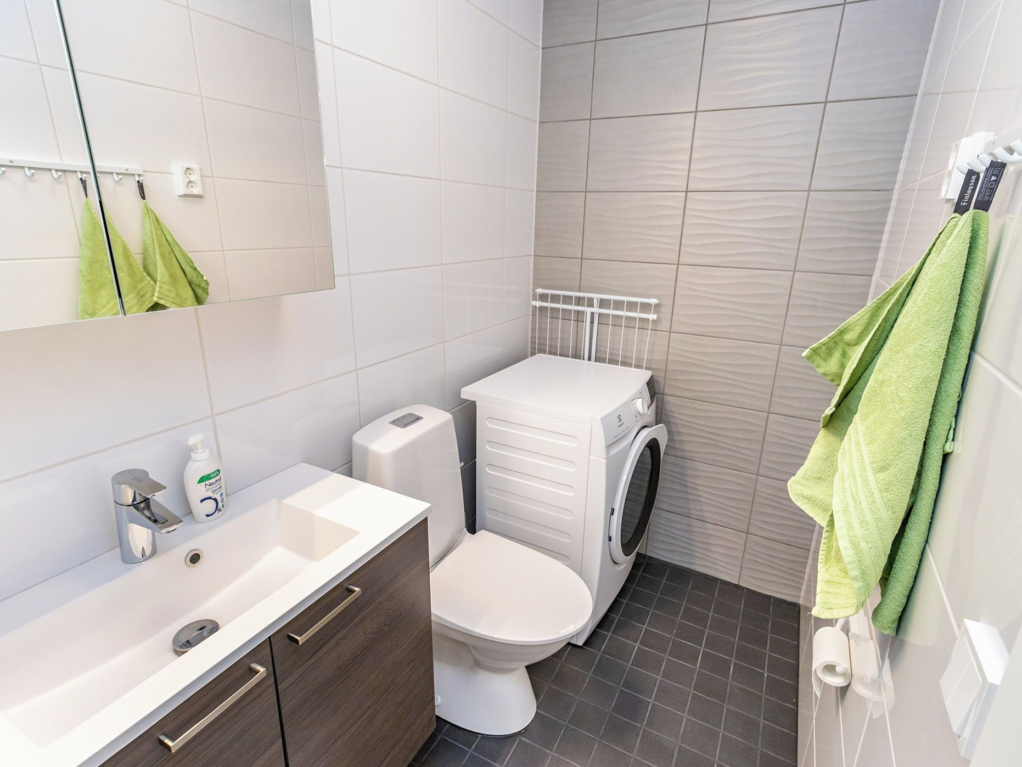 Moderni kylpyhuone, jossa on valkoinen pesuallas, wc ja pesukone.