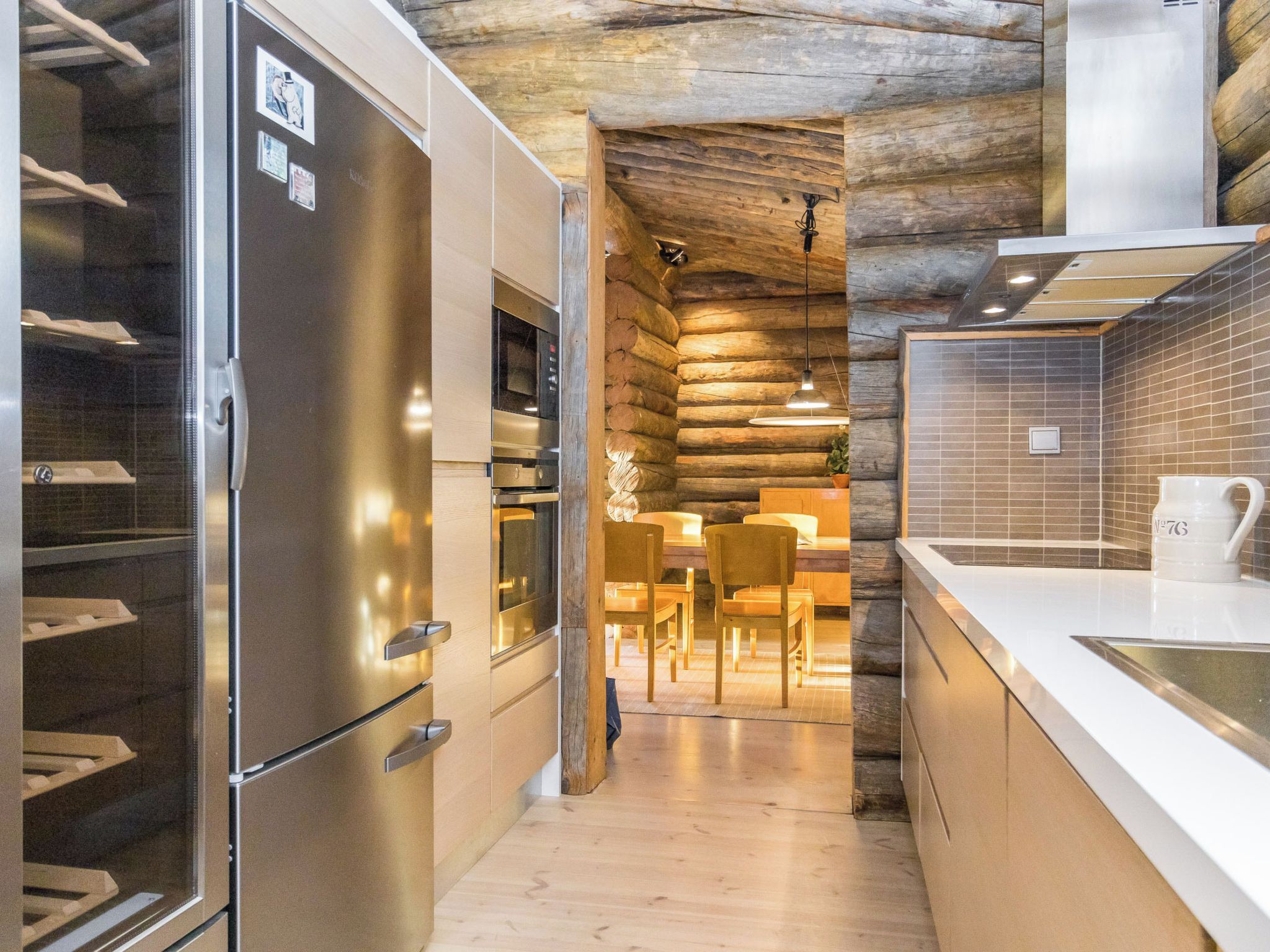Una cocina moderna con electrodomésticos de acero inoxidable, paredes de madera y una zona de comedor con sillas y una mesa.