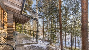 A log cabin with a wooden deck and a bench, surrounded by a snowy forest. - Kaasavuoren ranta by Interhome (Naantali)
